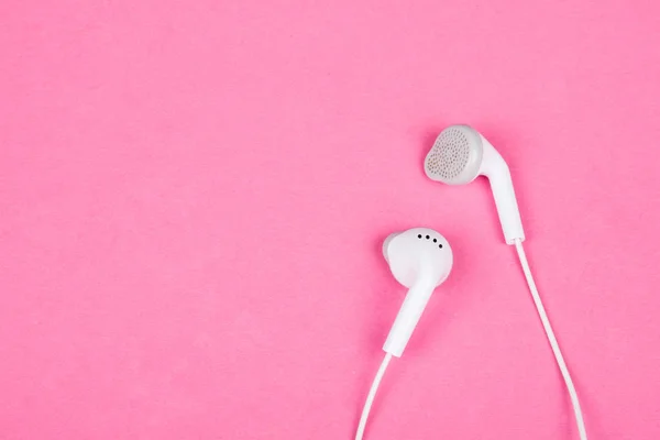Pembe arka planda beyaz kulaklıklar