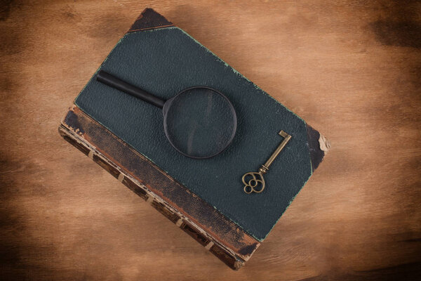 Old book, a key and a magnifying glass