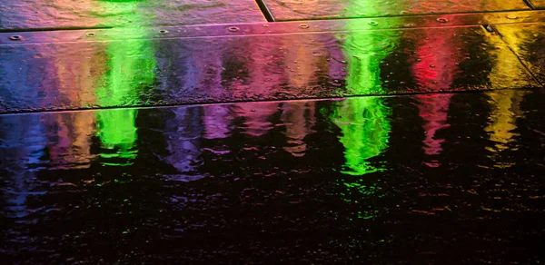 Rozmazaná neonová městská světla reflektaná v kaluži — Stock fotografie