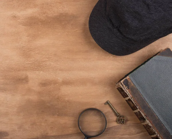 Cap of a detective, a book, a key and a magnifying glass