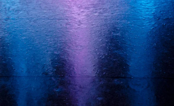 Bulanık neon şehir ışıkları bir su birikintisi yansıyan