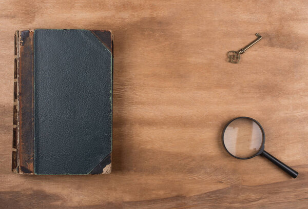Old book, a key and a magnifying glass