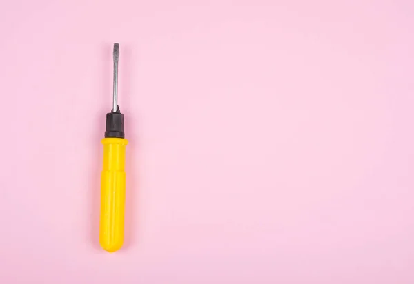 Gele schroevendraaier op een pastel roze achtergrond — Stockfoto