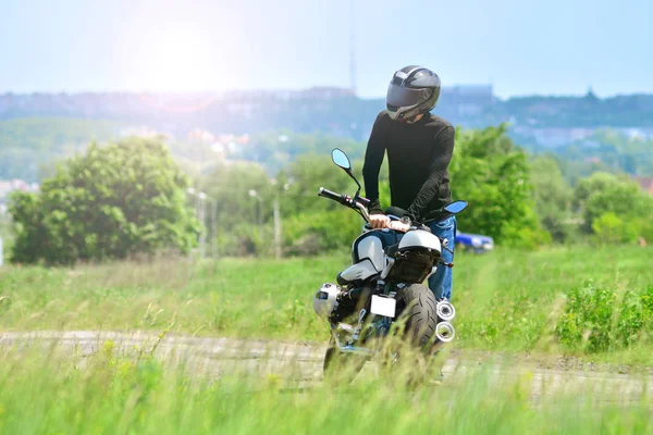 骑自行车 摩托车司机在头盔附近 他的摩托户外 — 图库照片