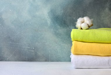 Doğal pamuk çiçek renkli pamuk havlu yığını. Banyo iç dekoratif sıva arka plan ile. Kopya alanı.