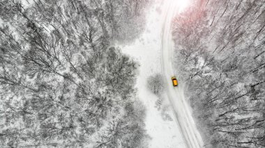 Hava. Güzel kırsal köy yolunda sarı araba kış sezonu ile orman arasında. 