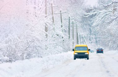 Kar yol kapalı. Sarı araba karlı bir yol üzerinde. Kış kaygan yolda sürüş. 