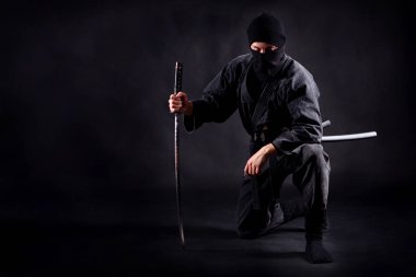 Ninja samurai crouched on one leg  and propped on a sword