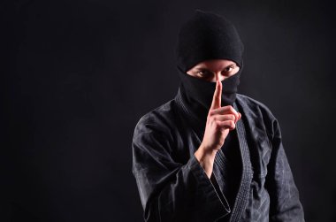 Sessiz olun! Şşş sembolü. Yün karanlık bir arka plan üzerinde suç ninja işaret parmağı dudaklarından tutar.. 