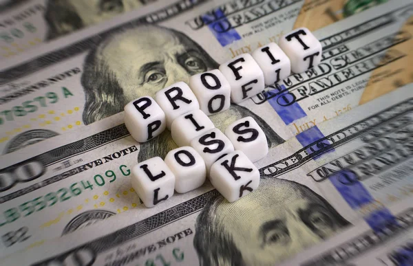 Profit or Loss, or Risk concept with letter cubes on a dollar bank notes.