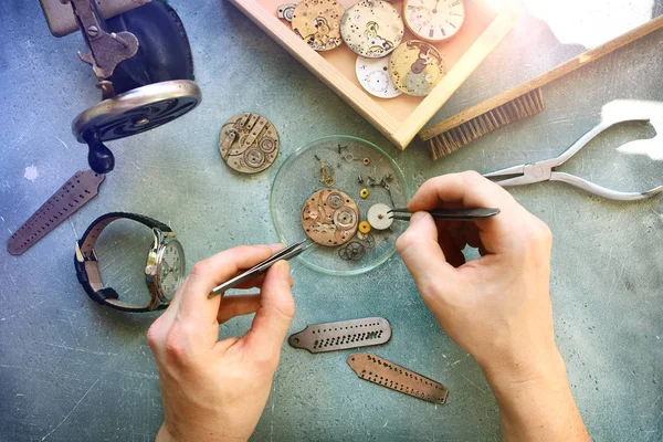 Watchmaker at work in workshop. Flat lay. Workplace of watch repairer. Process of repair mechanical watches