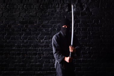 Saldırıda katana ile Ninja samuray koyu tuğla duvar arka plan üzerinde poz