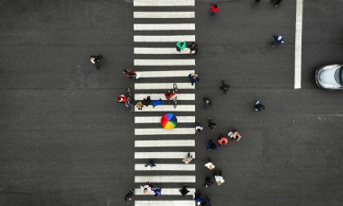 Hava. İnsanlar yaya geçidinde toplanıyor. Zebra geçidi, üst görüş. Kalabalıktan bir kişi renkli şemsiye tutar. 