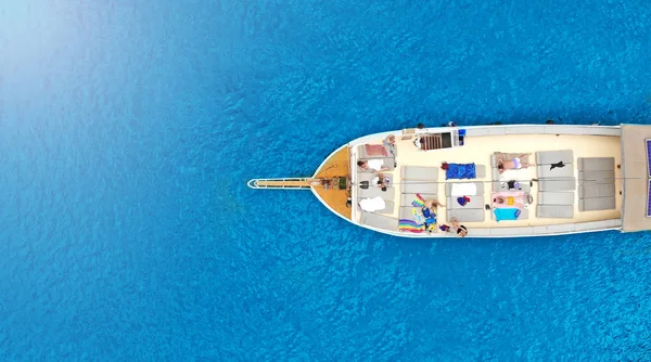 Boat tour aerial, top view. Sightseeing boat with tourists sailing on the sea. Walk on the sea view from drone.