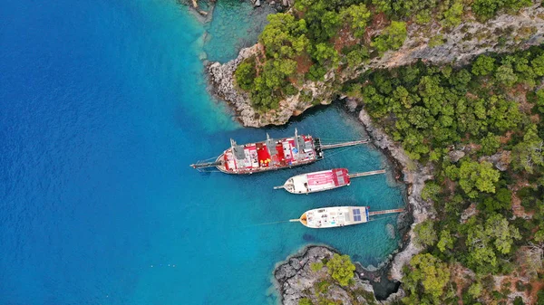 Touristic boats in the sea, top view. Aerial view of colorful boats standing abreast on the shore of the turquoise sea in azure water.