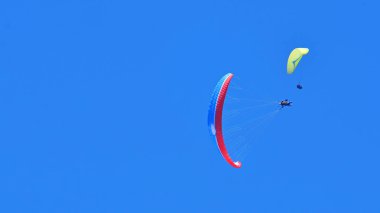 Yamaç paraşütü. Mavi gökyüzü arka planda iki yamaç paraşütü. Boşluk Kopyala.