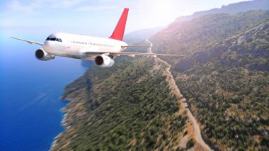 Deniz ve kıyı şeridinde yol ile uçan ticari uçak. Seyahat konsepti.