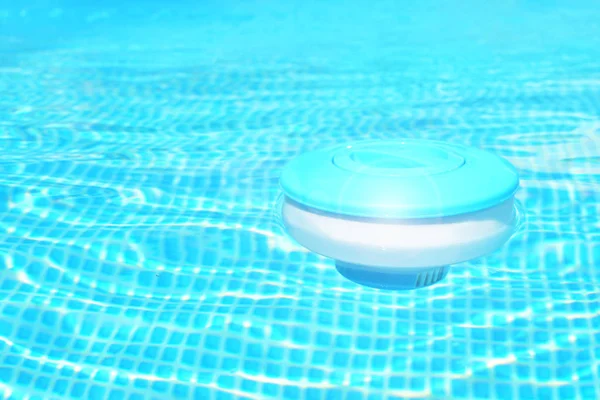 Pool cleaning chemicals background. Floating chlorine  tablet dispenser for pools lies in water.