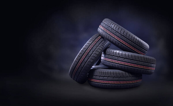 New tires pile on a dark background. Copy space. 