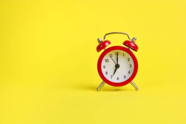 Red alarm clock on a yellow background. Copy space. clipart