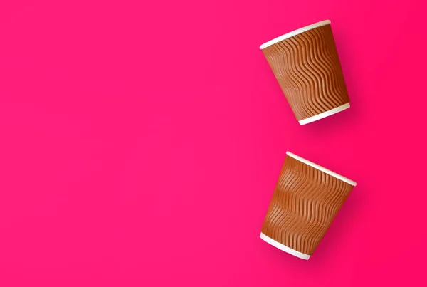 Coffee to go concept. Two paper cups of coffee on a pink background. Template with copy space.