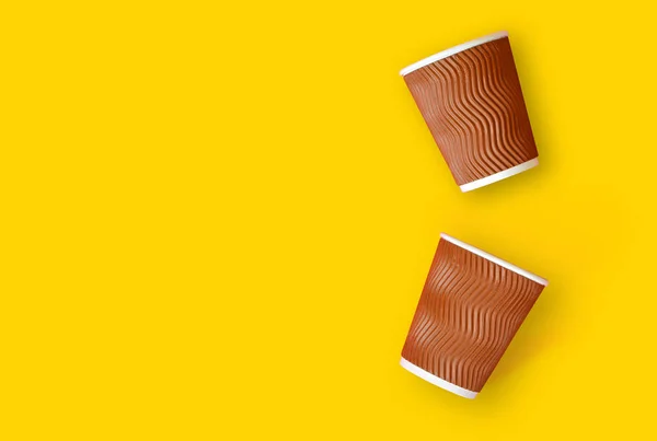 Coffee to go concept. Two paper cups of coffee on a yellow background. Template with copy space.