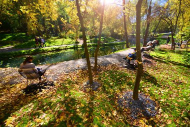 Kharkiv, Ukrayna - 2 Ekim 2019: İnsanlar göletli bir sonbahar parkında dinleniyor ve yürüyor