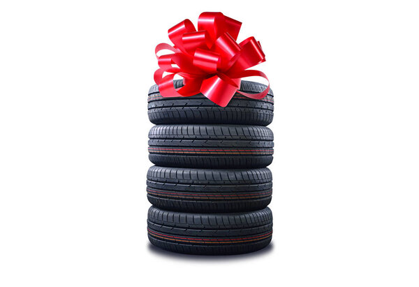 New tires pile as a gift  isolated on white. Tyres pile with a big red bow, as a present or bonus for buying a car.