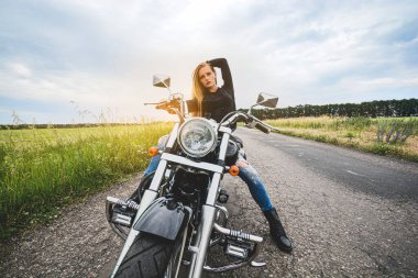 Motosiklet süren şık bir kız. Bir tarlada yolda durdu. Uzağa bakıyor.. 