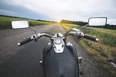 Motosiklet direksiyonu kırsal asfalt yola karşı. Birinci kişi görünümü. 