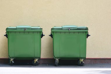 Çöp tenekeleri duvarın yanında.