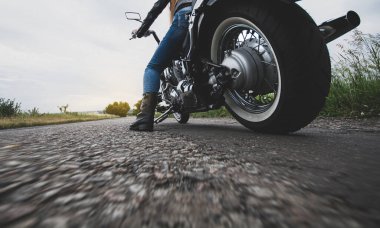 Motosikletli kadın motoru çalıştırdı ve hızlı gitmeye hazır.