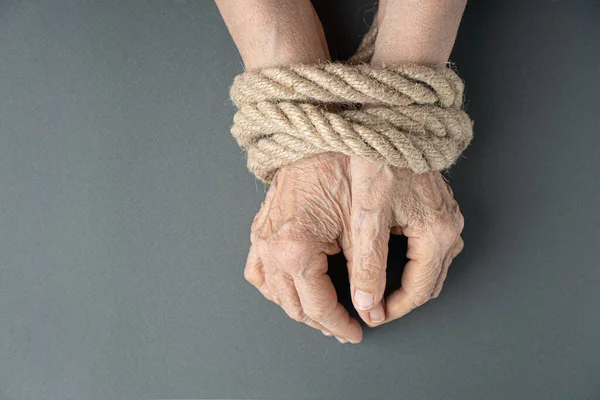 Elderly woman wrinkled hands tied with rope