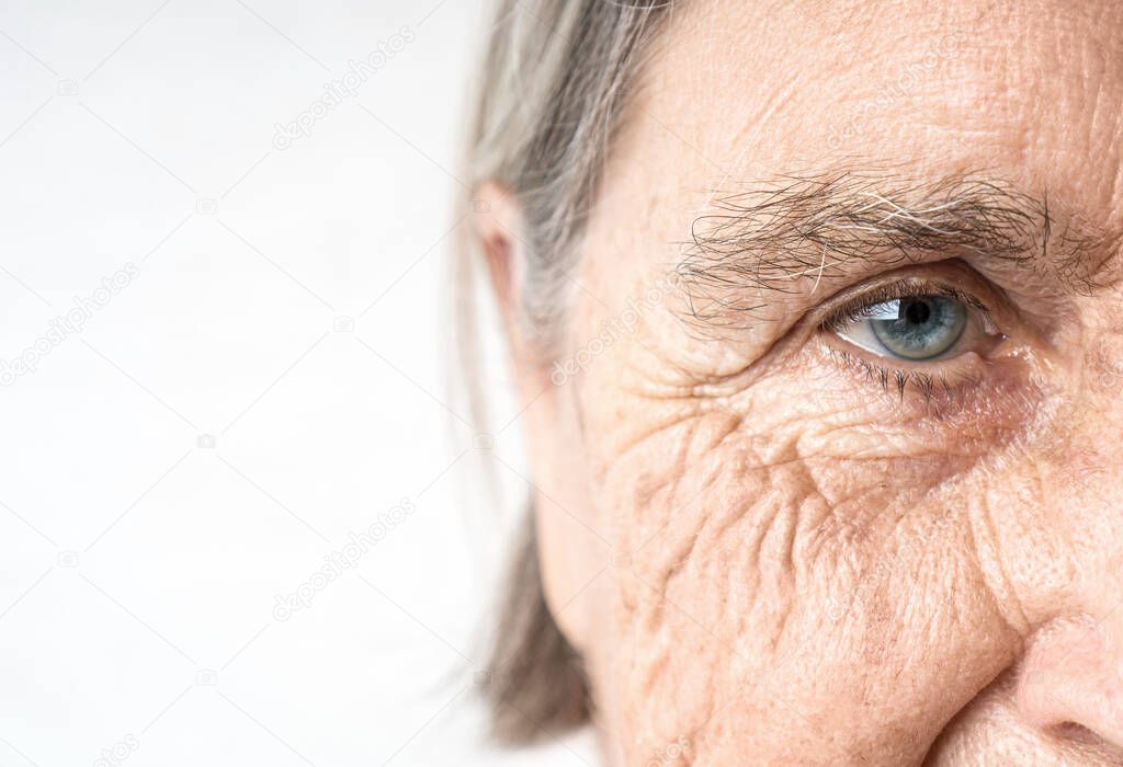 Elderly woman old eye and wrinkled face. Fragment of the portrait. Copy space.