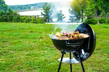 Doğada barbekü zamanı. Resimli bir gölün kıyısında barbekü partisi. Boşluğu kopyala. 