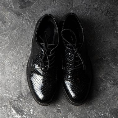 Beton zeminde duran şık uniseks siyah ayakkabılar. Üst görünüm.