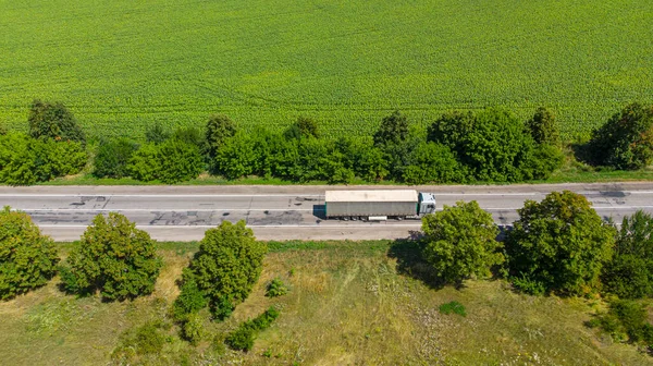 Aerial. Commercial truck driving by the roadway along the agricultural field.