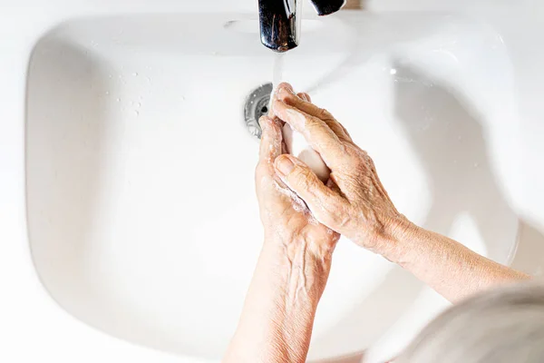 Elderly woman hands washing. Top view. Hand hygiene to prevent infection. Take care of the elderly.