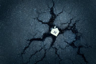 Kırık bir asfalt delikte küçük oyuncak evle konutların tahrip edilmesi kavramı.