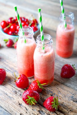 Ahşap masada çilekli kırmızı smoothie.