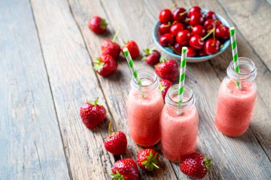 Ahşap masada çilekli kırmızı smoothie.