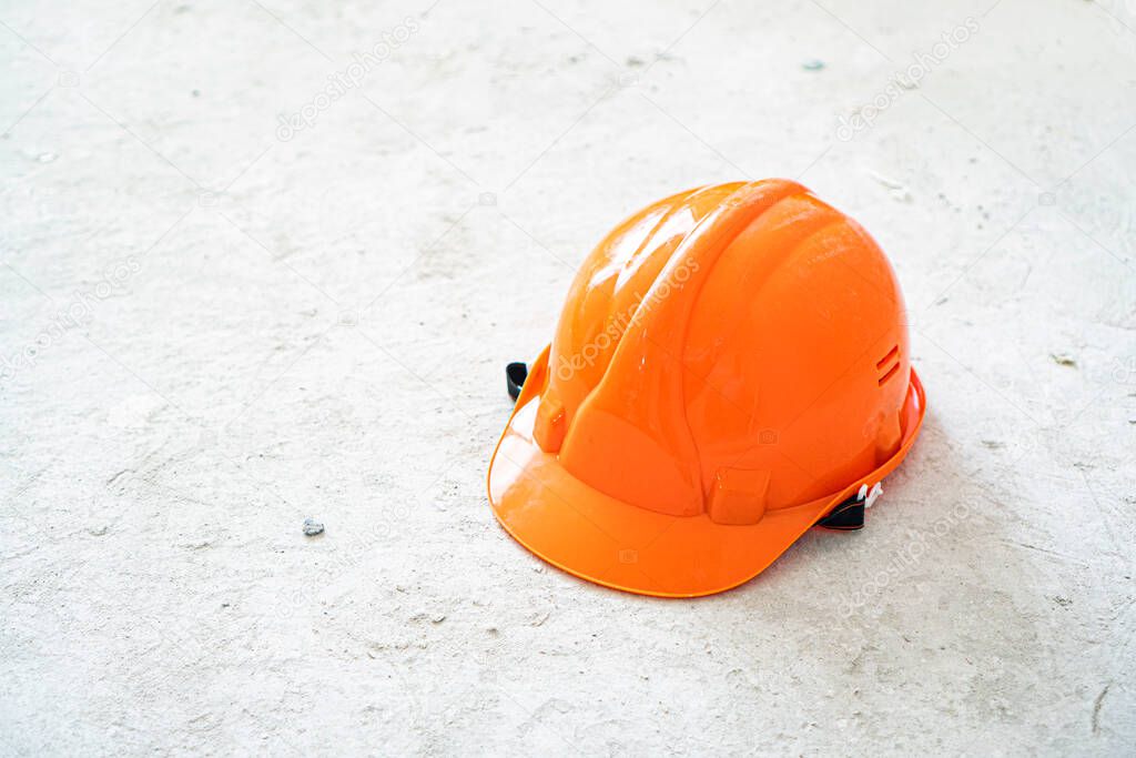 Orange safety hardhat on a conrete background. Building and constructing idea. 