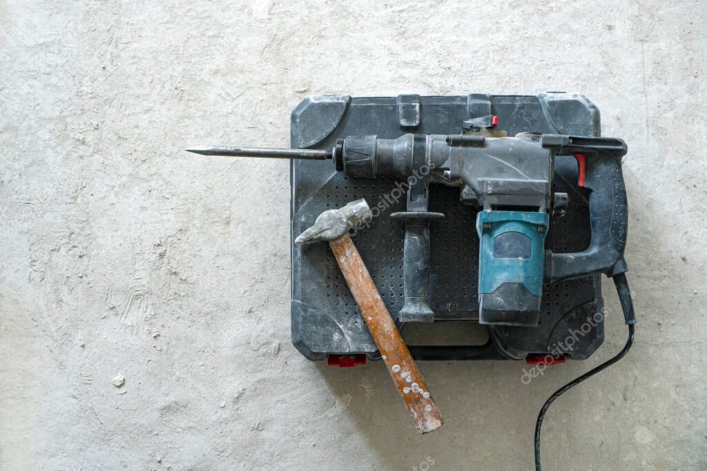 Dismanting concept. Rotary hammer for construction destroying and hand hammer on the concrete background. 