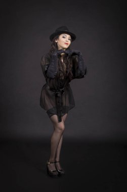 Siyah ceket, siyah eldiven ve siyah şapka dans güzel genç kız. Karanlık bir arka plan üzerinde stüdyoda poz, görüntü izole.