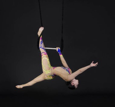 Genç bir kız akrobatik öğeleri hava trapez gerçekleştirir. Stüdyo performansları bir siyah arka plan üzerinde çekim.