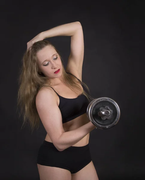 Een jonge vrouw die zich bezighouden met fitness met halters. — Stockfoto