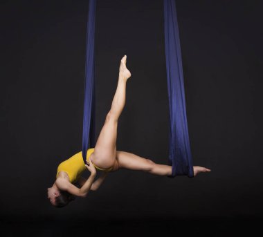 Genç gülümseyen kız bir döngü hava ipek egzersizleri yapıyor. Karanlık bir arka plan üzerinde çekim stüdyo.