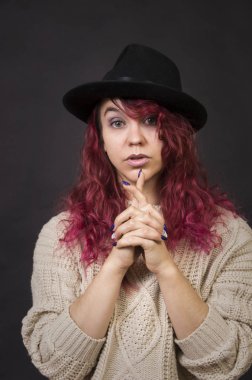 Bir şapka ve koyu bir arka plan Studio.Isolated görüntülerde poz uzun saçlı kazak duygusal esmer.