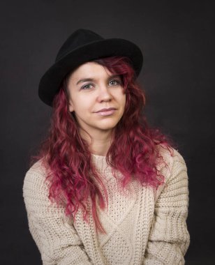 Bir şapka ve koyu bir arka plan Studio.Isolated görüntülerde poz uzun saçlı kazak duygusal esmer.