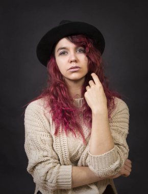 Bir şapka ve koyu bir arka plan Studio.Isolated görüntülerde poz uzun saçlı kazak duygusal esmer.